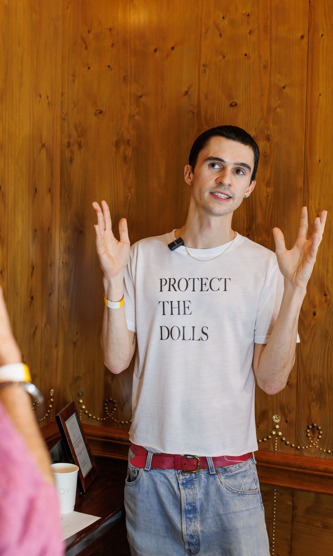 Conner Ives in his Protect The Dolls tshirt at his FW25. He wears the white t-shirt with jeans and a red belt.  runway show