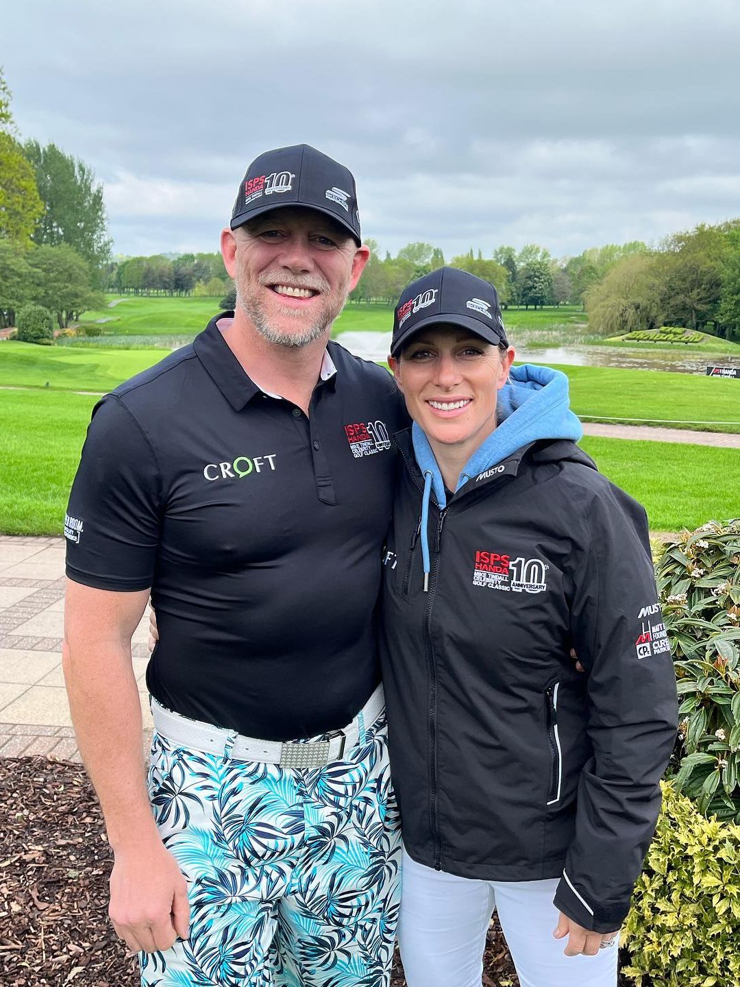 couple posing at golf course in caps 