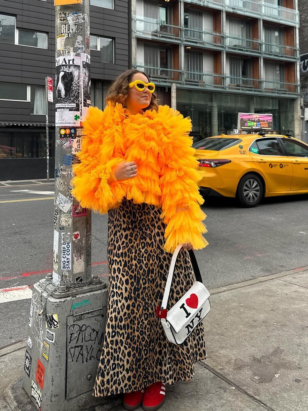 Style muse @styled.daisy wears a fluffy orange jacket, leopard print skirt and red trainers while out in NYC