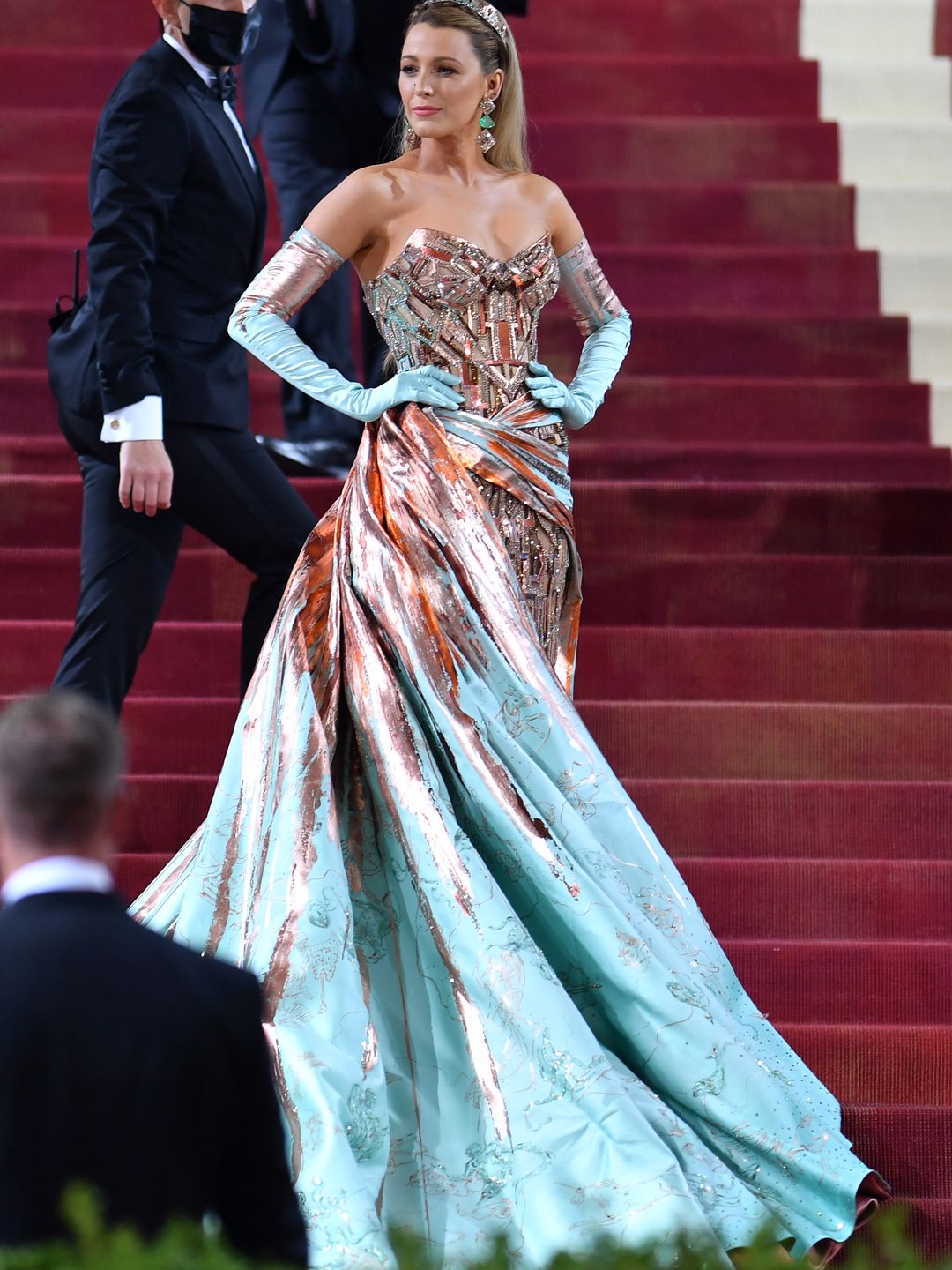 Blake Lively stood on red carpet steps posing in her long pink and green glittery gown