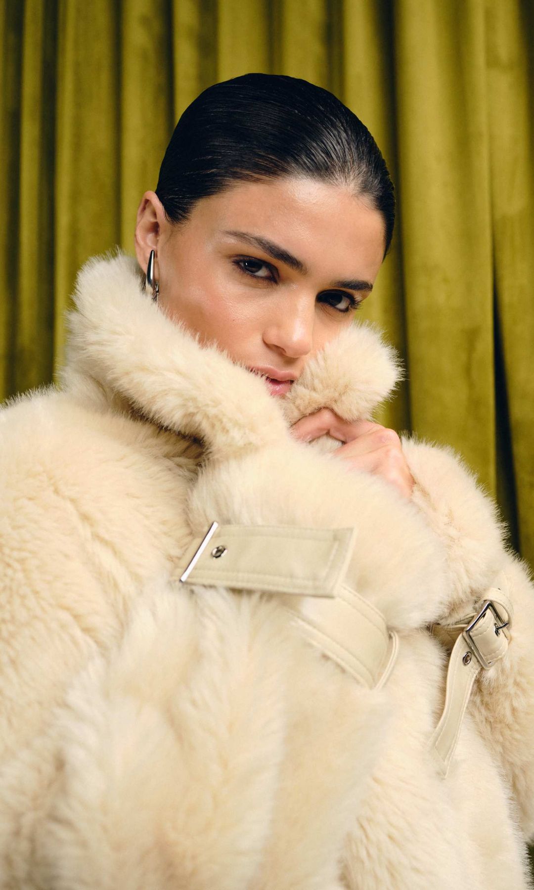 Asos model wearing a firry coat in front of a green background