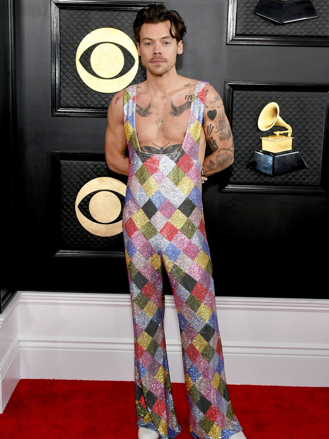 Harry Styles attends the 65th GRAMMY Awards wearing a multicoloured jumpsuit and white bots
