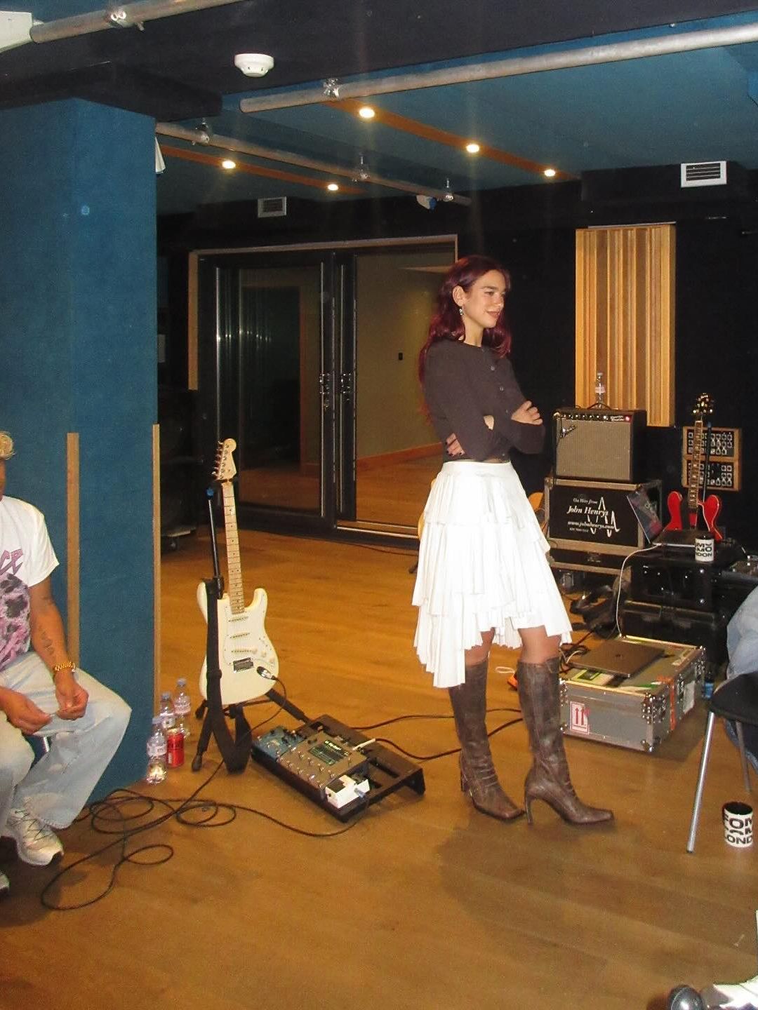 Dua Lipa shares an image of herself in the music studio wearing knee-high boots and a white skirt