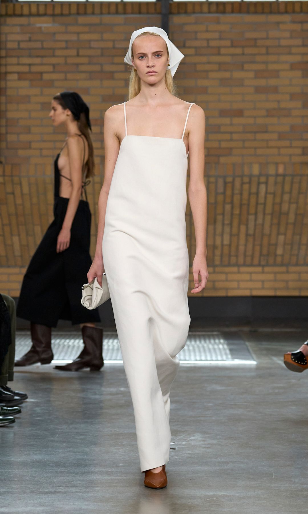 A model wears a white strappy slip dress with matching white headband and brown shoes