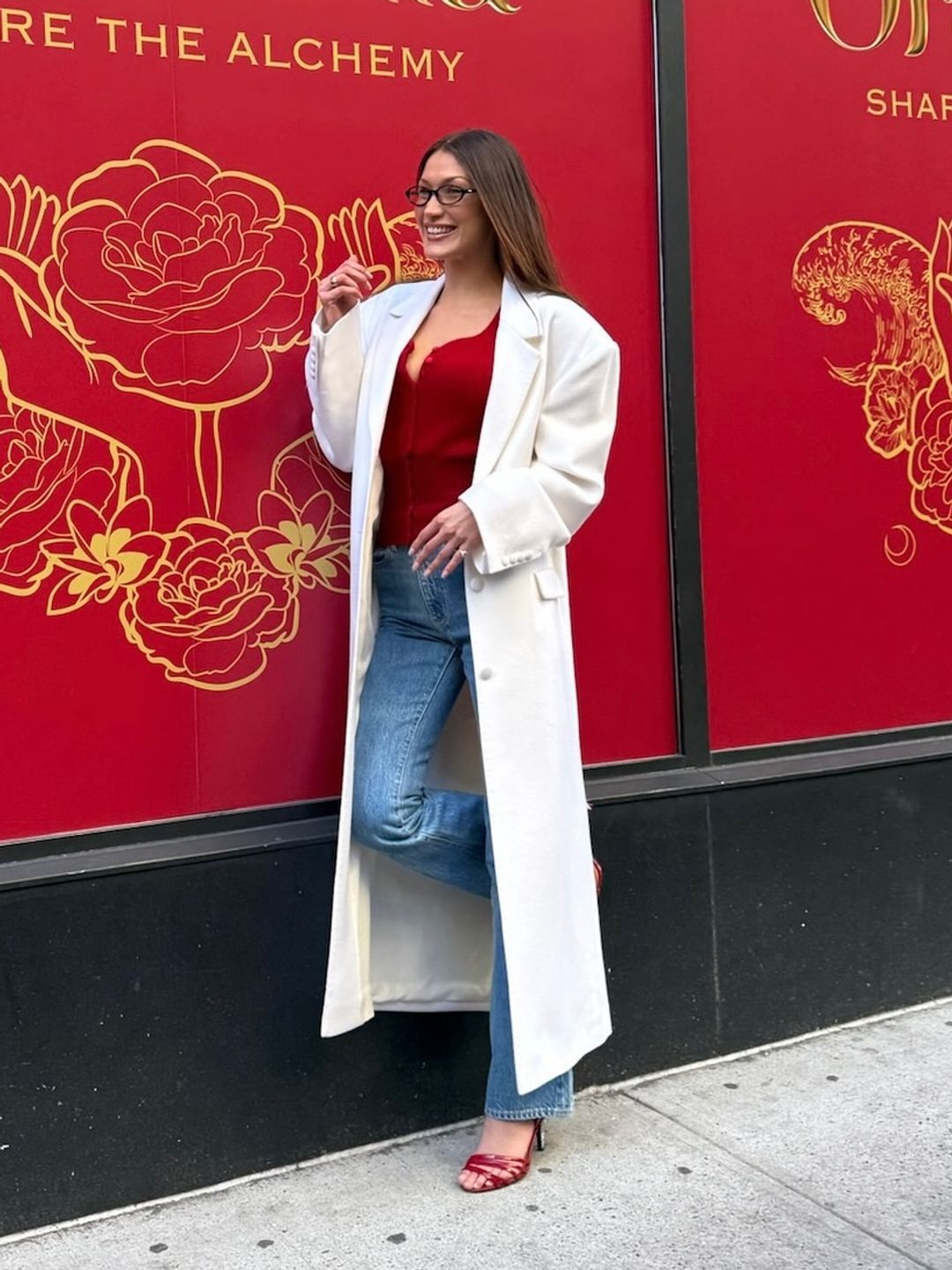 Bella Hadid poses in jeans, heels, a red cardigan and white coat on her Instagram