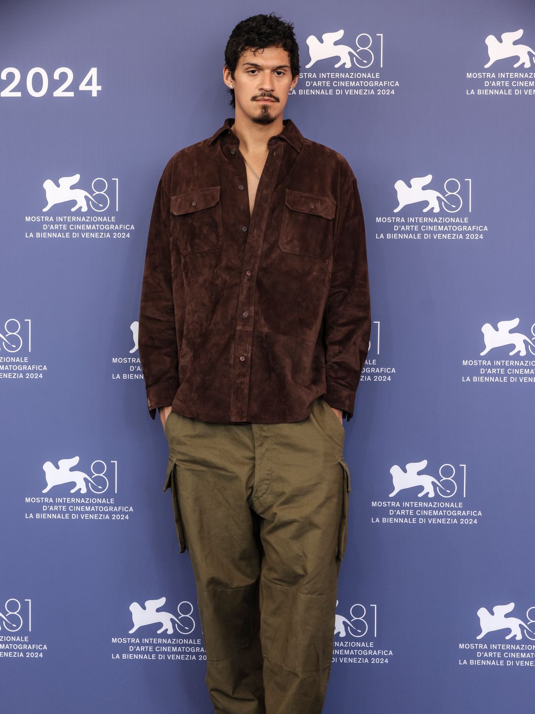 Omar Apollo in a brown shirt and green trousers