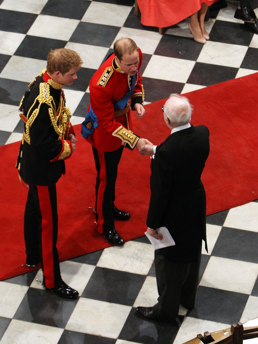 Prince William and Prince Harry shaking hands with an elderly gentleman at William's wedding