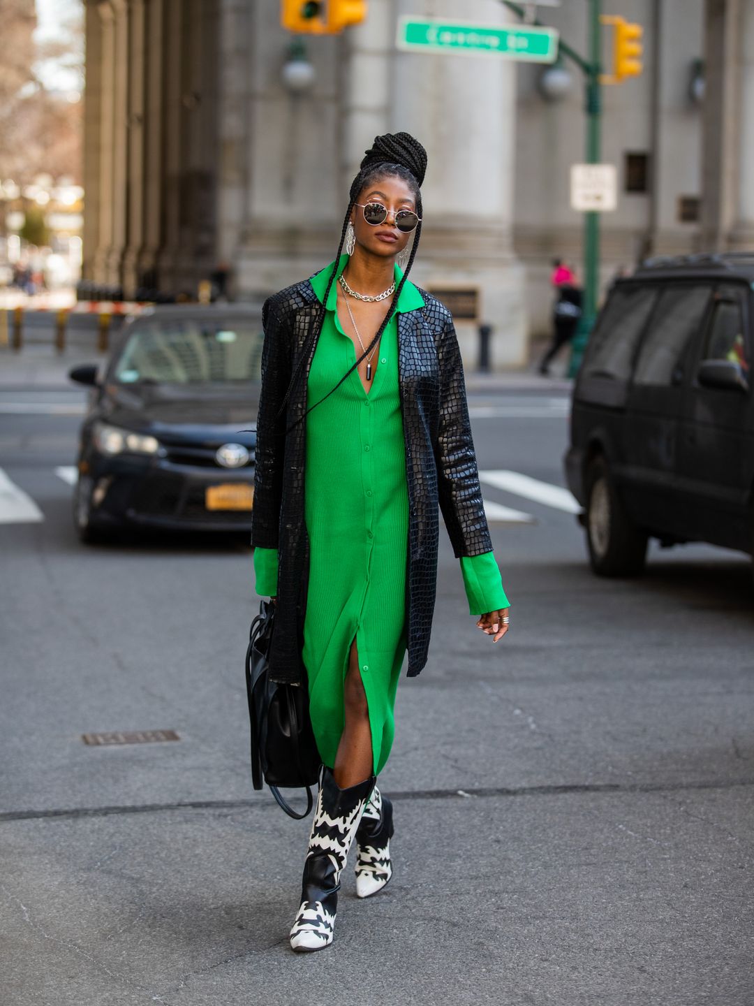 A Fashion Week guest styles a green shirt dress with black and white cowboy boots 