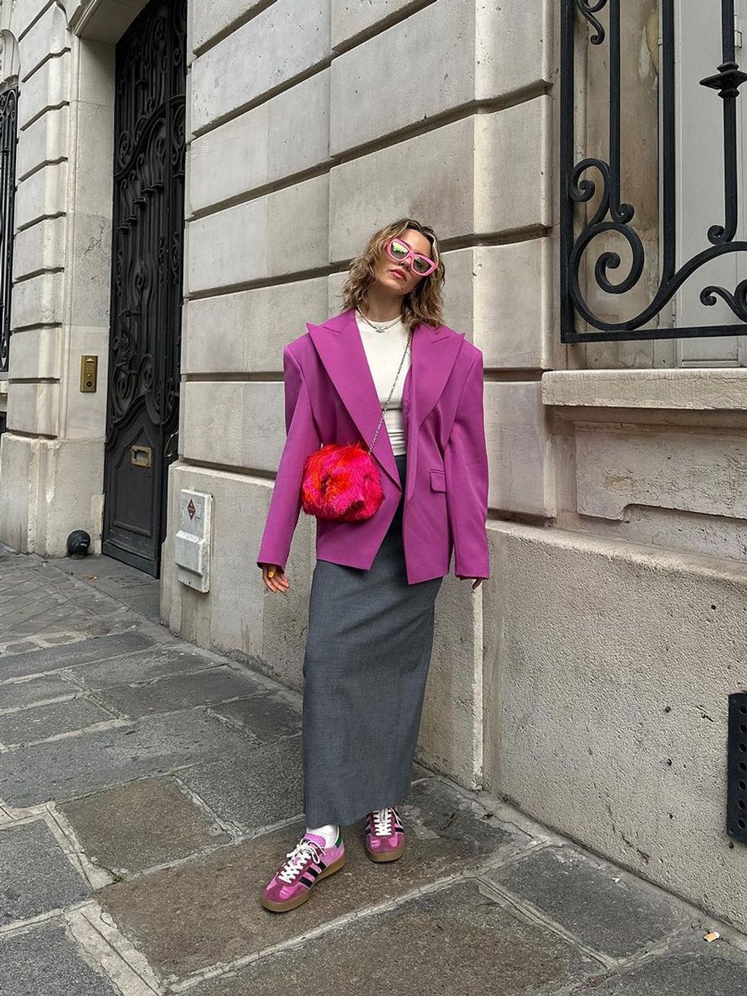 Influencer Maxine Wylde wears a grey skirt with bright purple sneakers and blazer 
