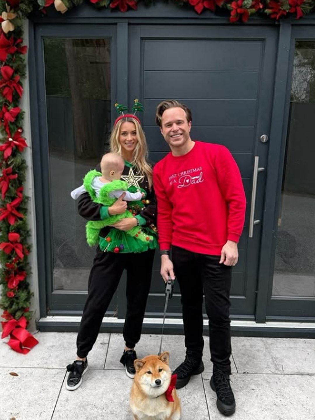 Amelia Tank holding a baby and standing with Olly Murs outside their home