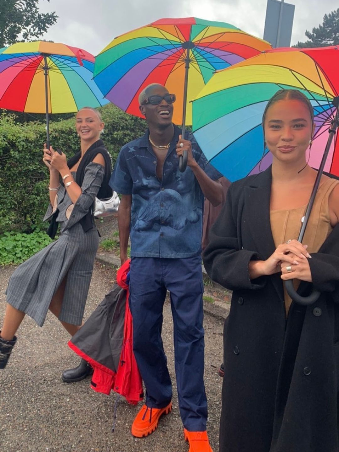 Mia Regan holding a colourful umbrella alongside two others 
