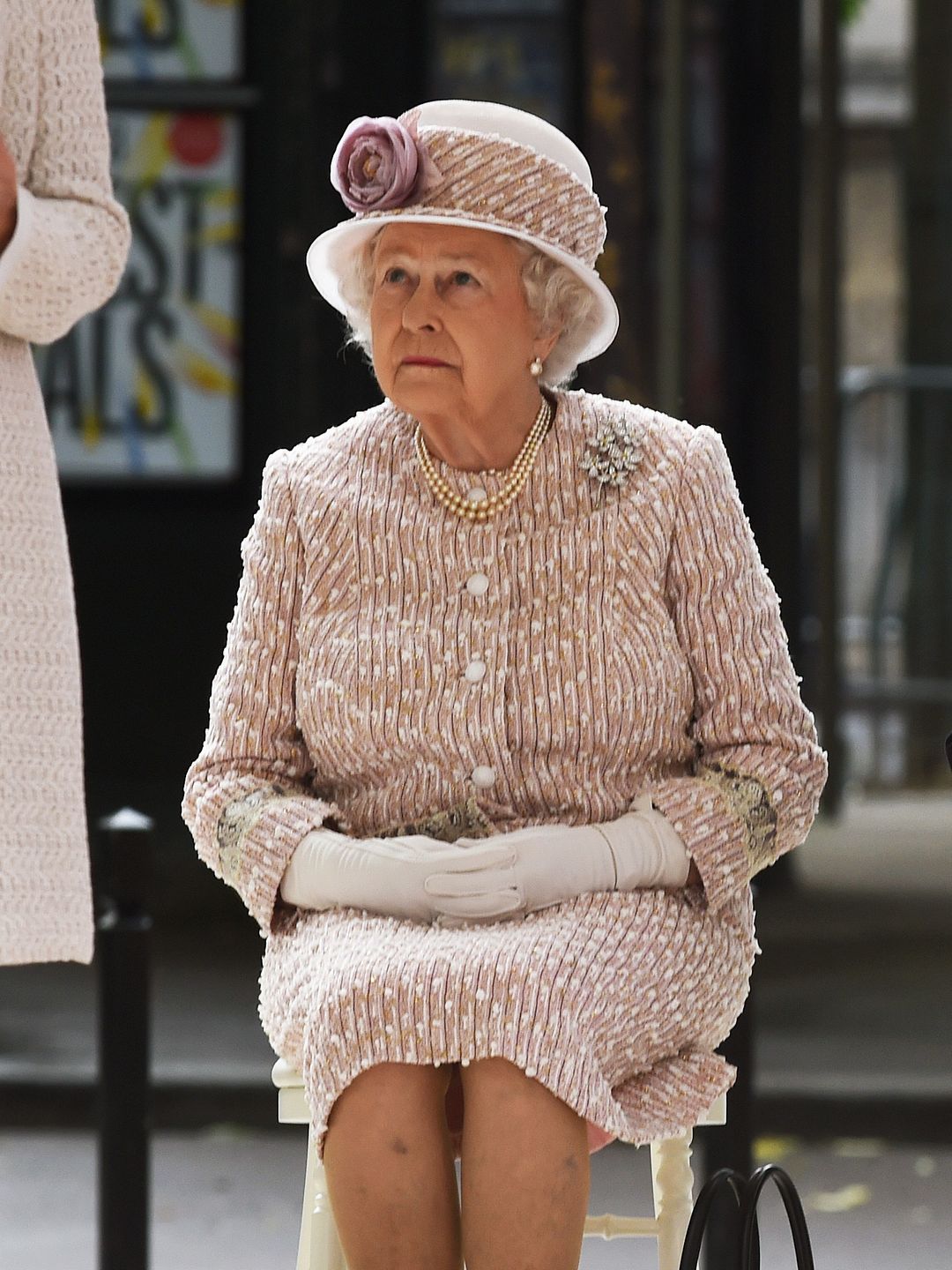 queen on chair with black handbag 