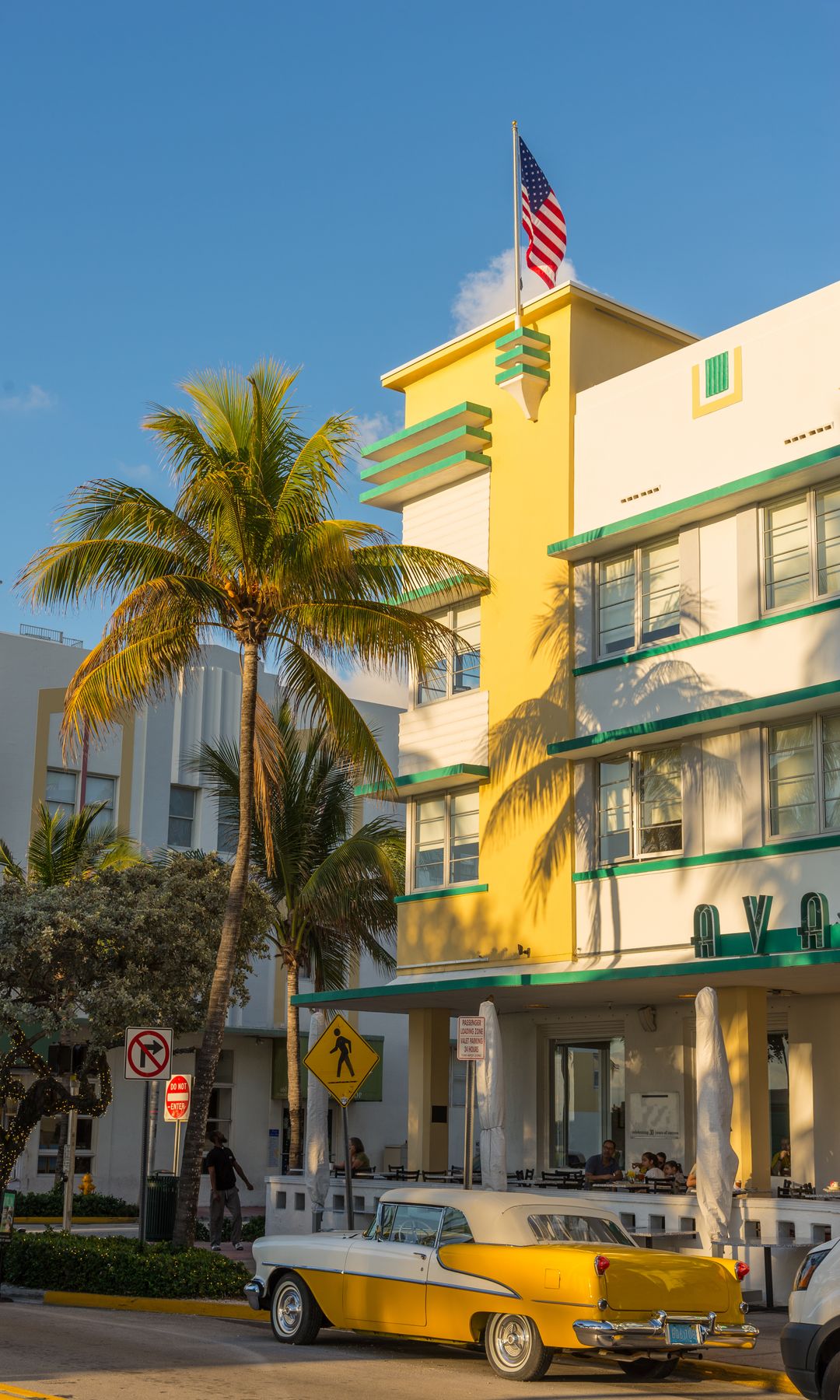 Early morning sunrise on the Art Deco styled Avolon Hotel facade on Ocean Drive  with vintage car parked at the curb