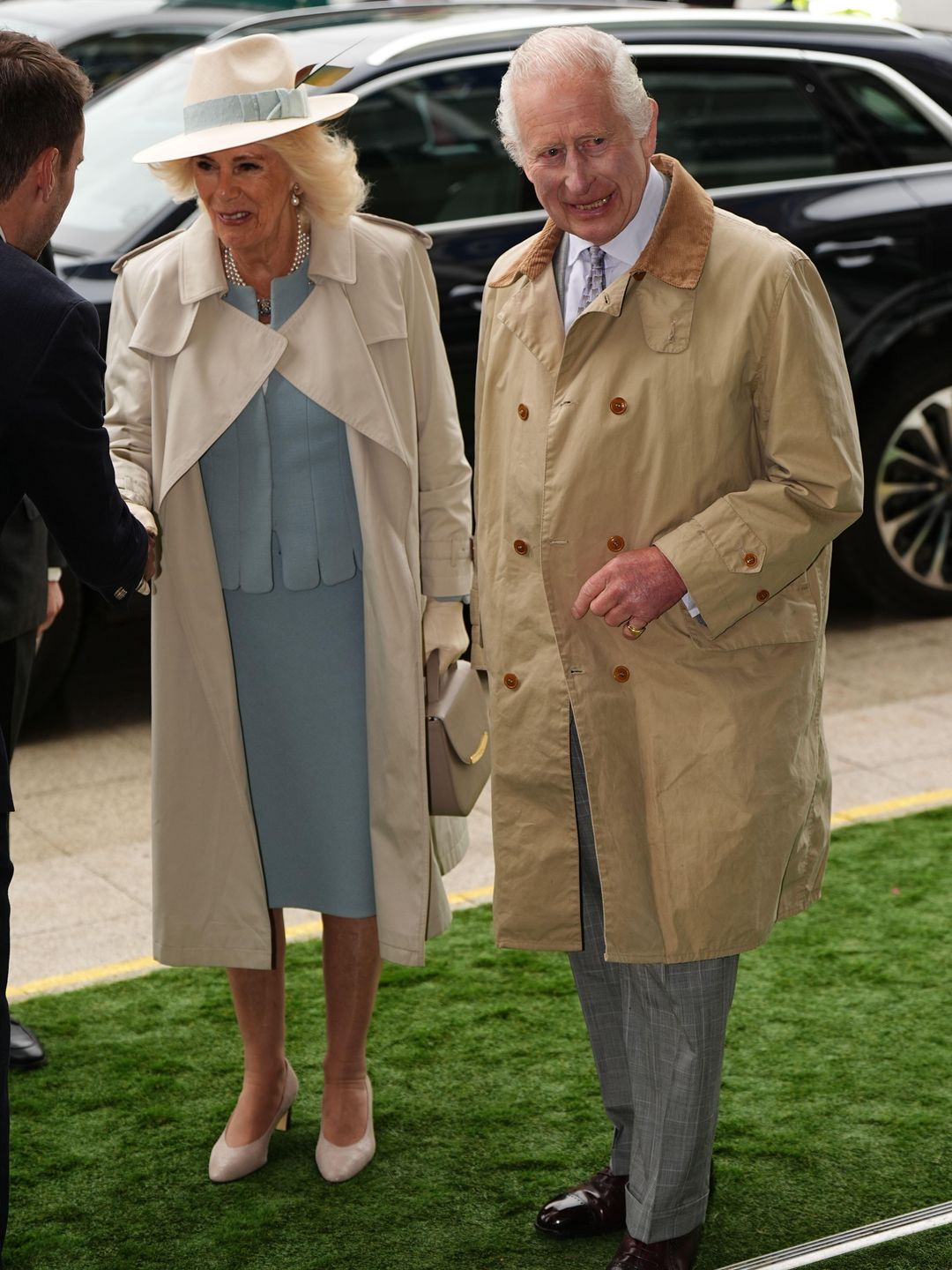 Queen Camilla and King Charles in raincoats