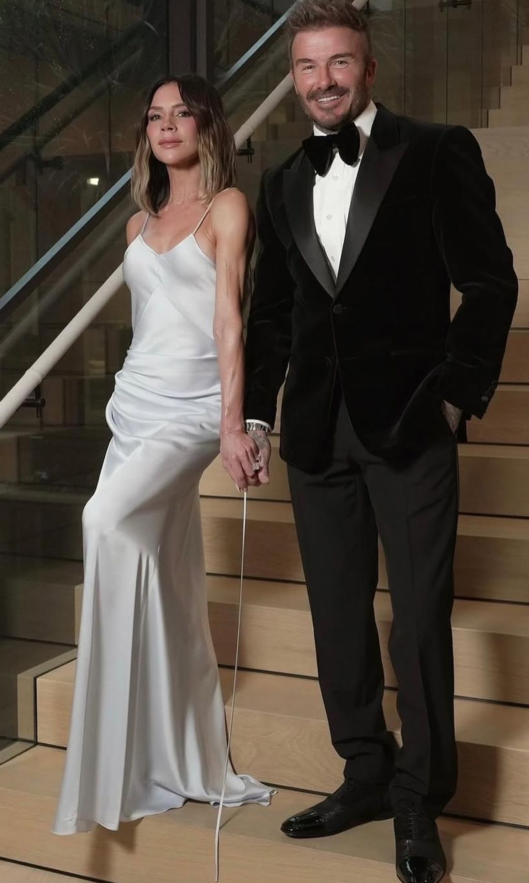 Victoria Beckham poses next to her husband David in a white silky gown