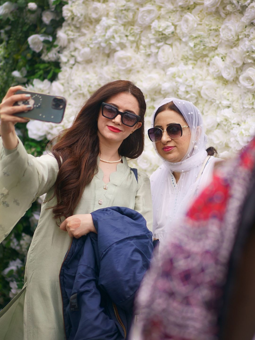 People celebrate during the Eid in the Square festival in Trafalgar Square, London by taking a selfie infront of a floral wall