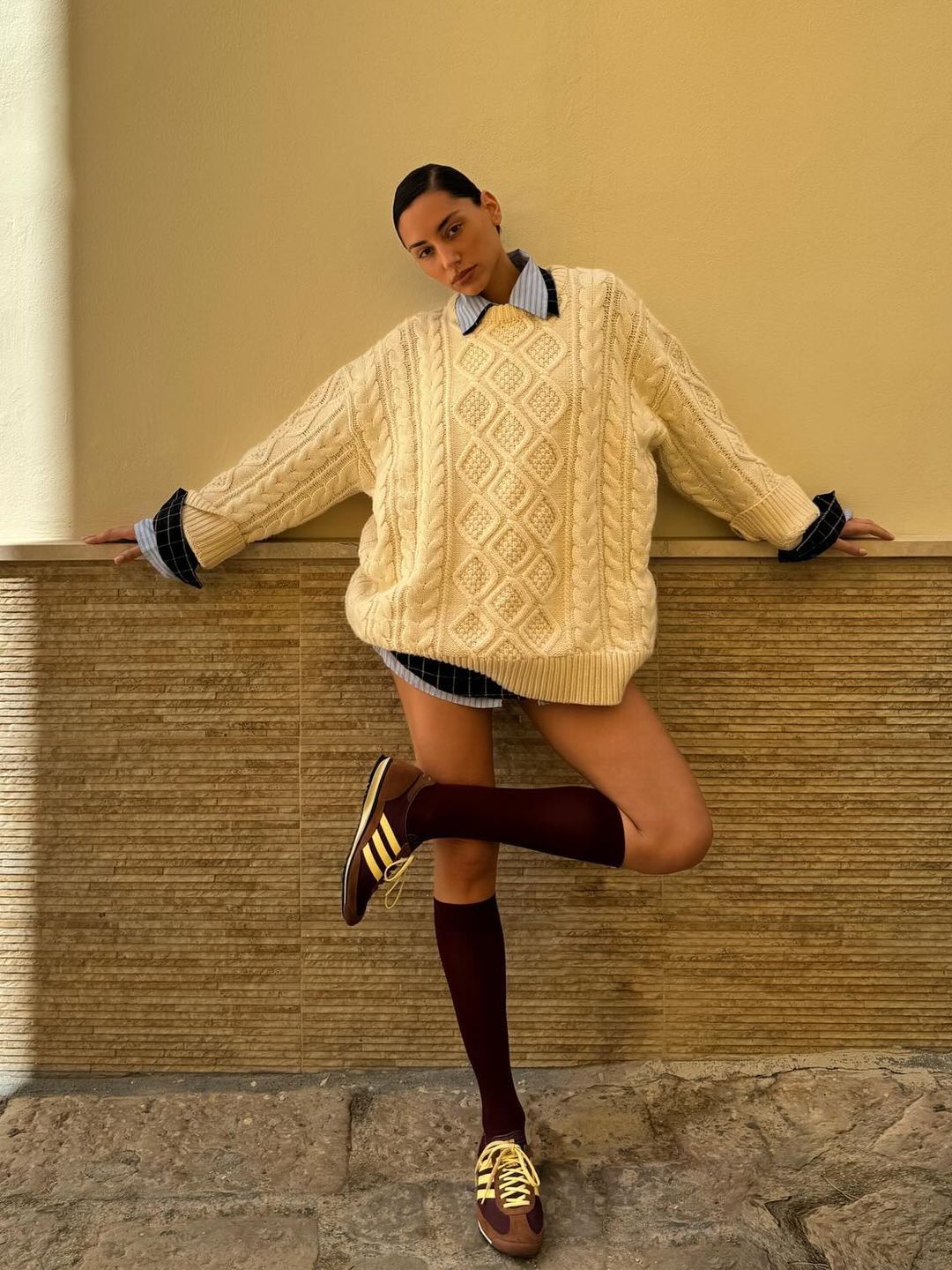 Influencer Olivia Pezzente poses in adidas trainers and a yellow jumper