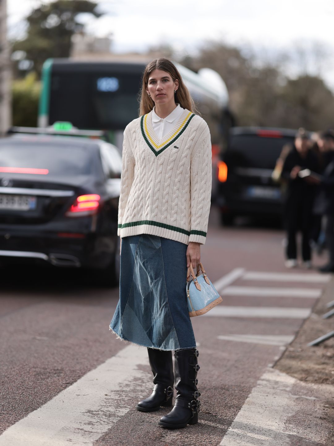 Veronika Heilbrunner seen wearing  cream and black Lacoste sweater, white shirt, blue denim jeans skirt and black boots with tan and light blue bag outside Lacoste Show during the Womenswear Fall/Winter 2024/2025