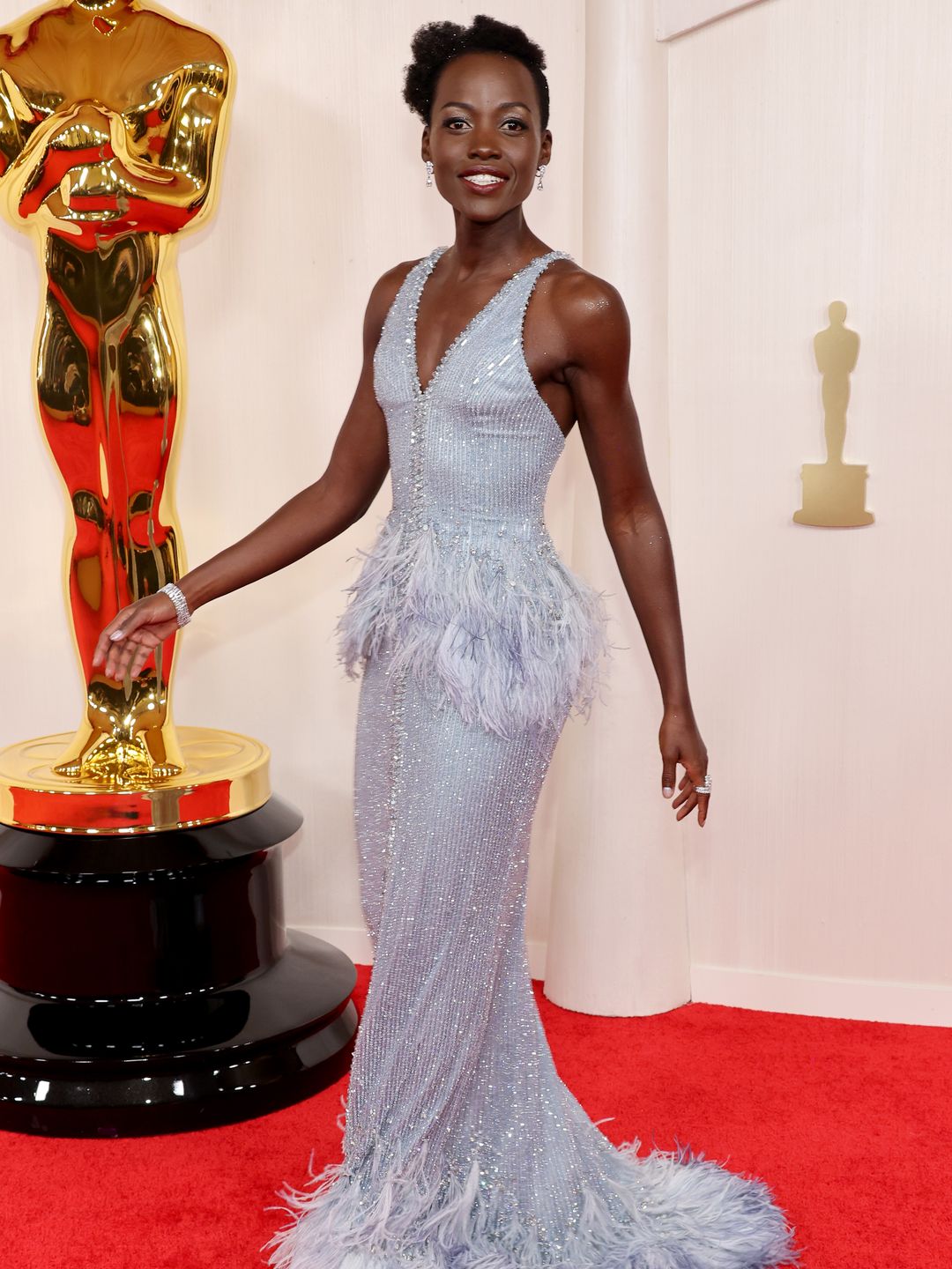 Lupita Nyong'o attends the 96th Annual Academy Awards  in a dove grey feather fringed gown