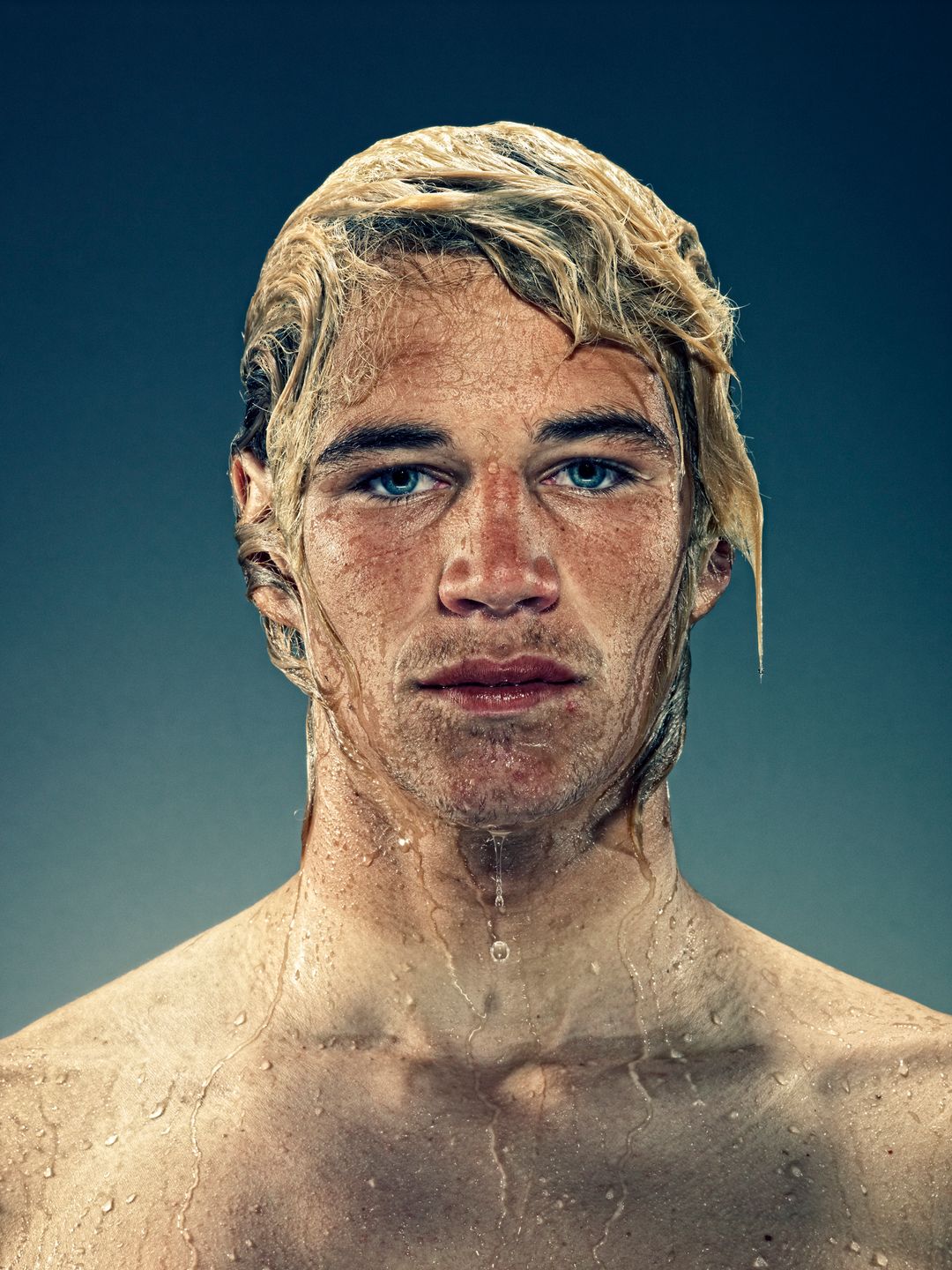 Caucasian male with wet hair and face, intense blue eyes and tan line