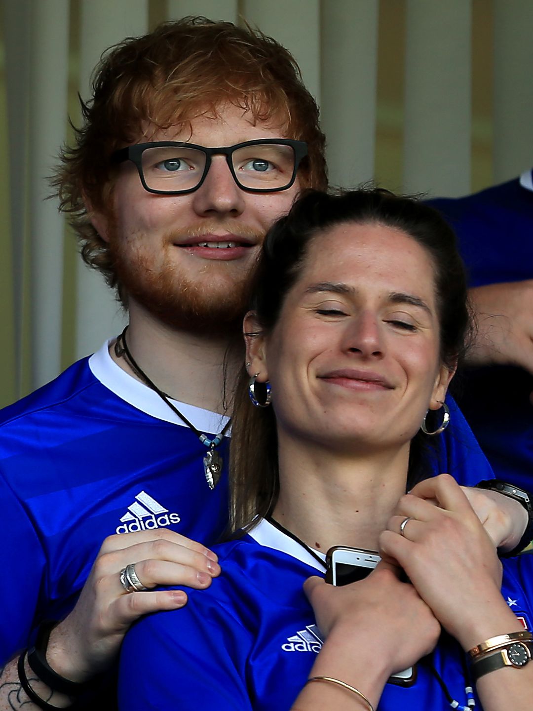 Ed Sheeran and Cherry Seaborn at a football game, she is resting her head on his shoulder