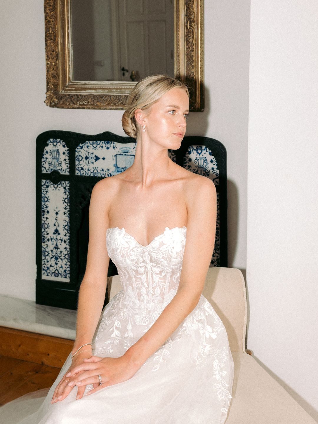 Bride sits down in her wedding dress and gazes into the distance 