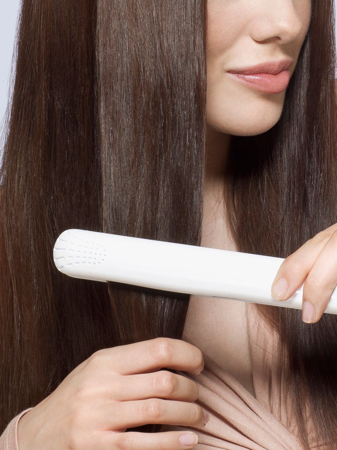 young woman with brown hair using straighteners