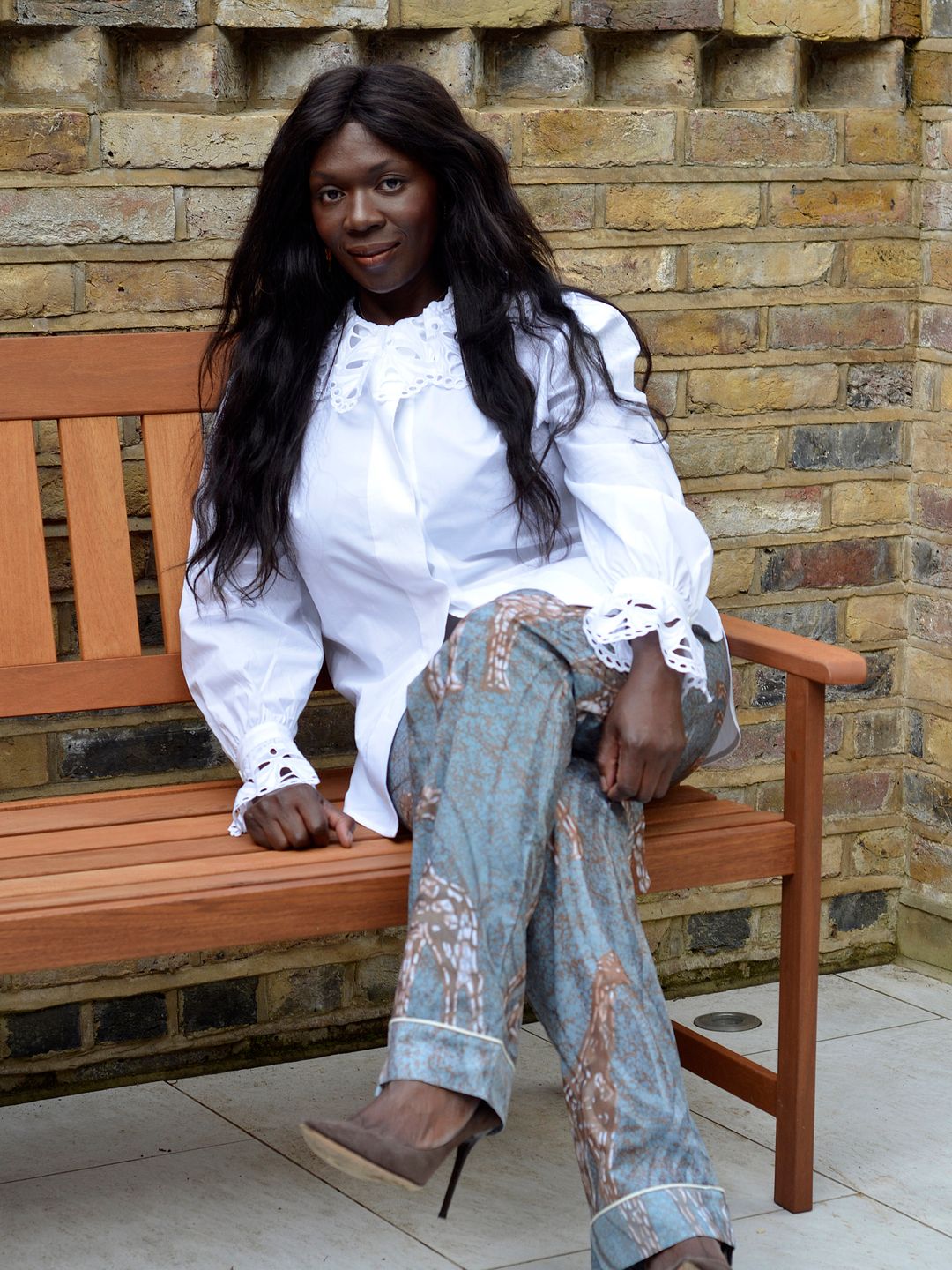 Tuvie Ejoh poses in a white shirt and jeans on a bench 