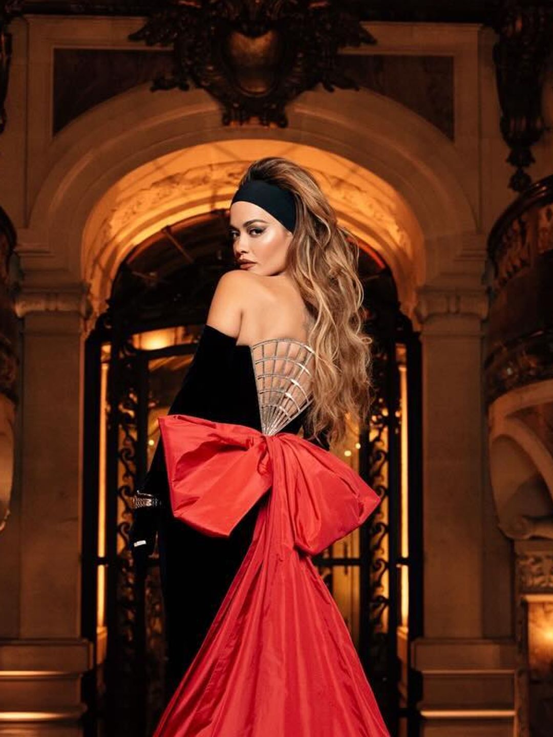 Rita Ora wears a thick black head band and gown at PFW 2024