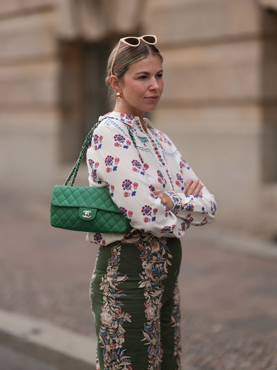 Aline Kaplan s seen wearing beige cat eye sunglasses; chunky golden hoop earrings; several golden necklaces; an outfit from SÃ©zane, consisting of a white long-sleeved shirt with floral pattern and a wide high-waisted pair of trousers in olive with floral pattern and a green leather vintage bag from Chanel on June 07, 2024 in Berlin, Germany. (Photo by Jeremy Moeller/Getty Images)