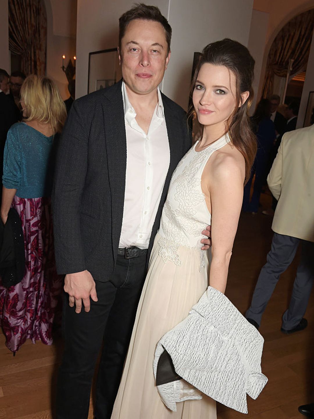 Elon Musk wearing a black suit and Talulah Riley wearing a white dress.