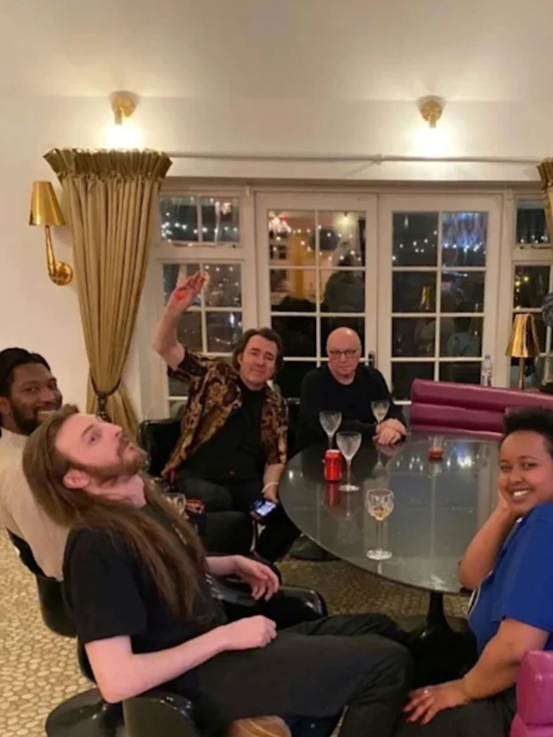 Jonathan Ross and a selection of people sat around a dining room table