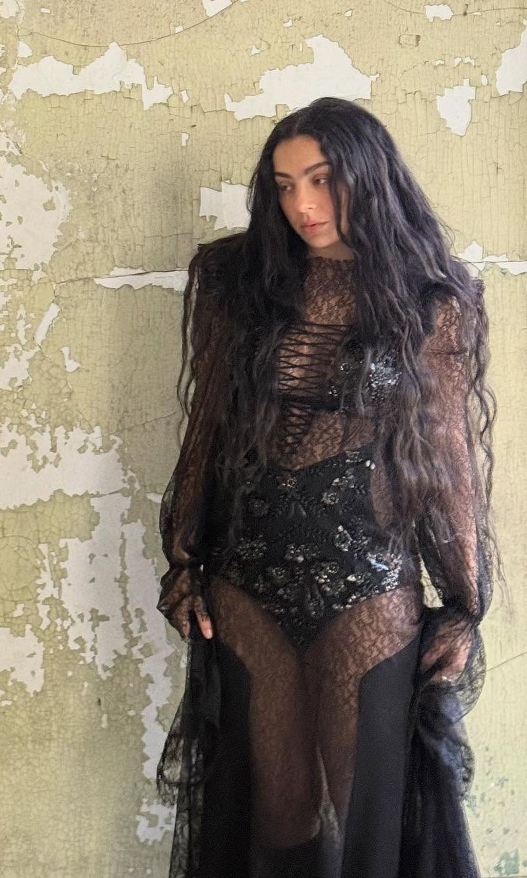 Charli XCX poses in a black lace dress
