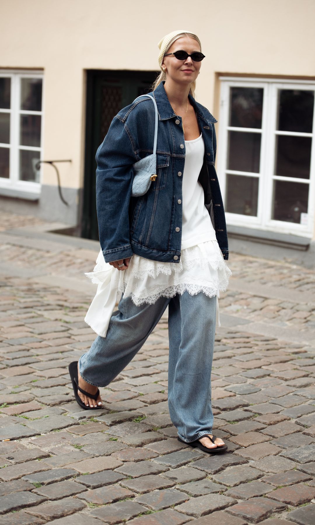  Hollie Mercedes Peters wears blue jeans, white dress with lace details, dark blue jacket from Balenciaga and butter yellow head scarf and blue bag outside Niklas Skovgaard 
