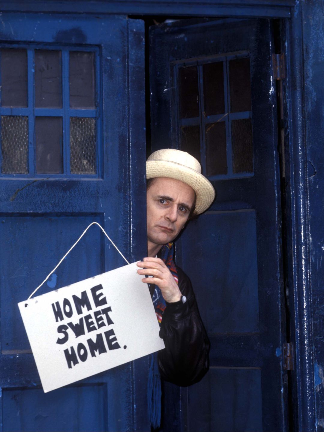 Sylvester McCoy in character as The Doctor inside a blue police box