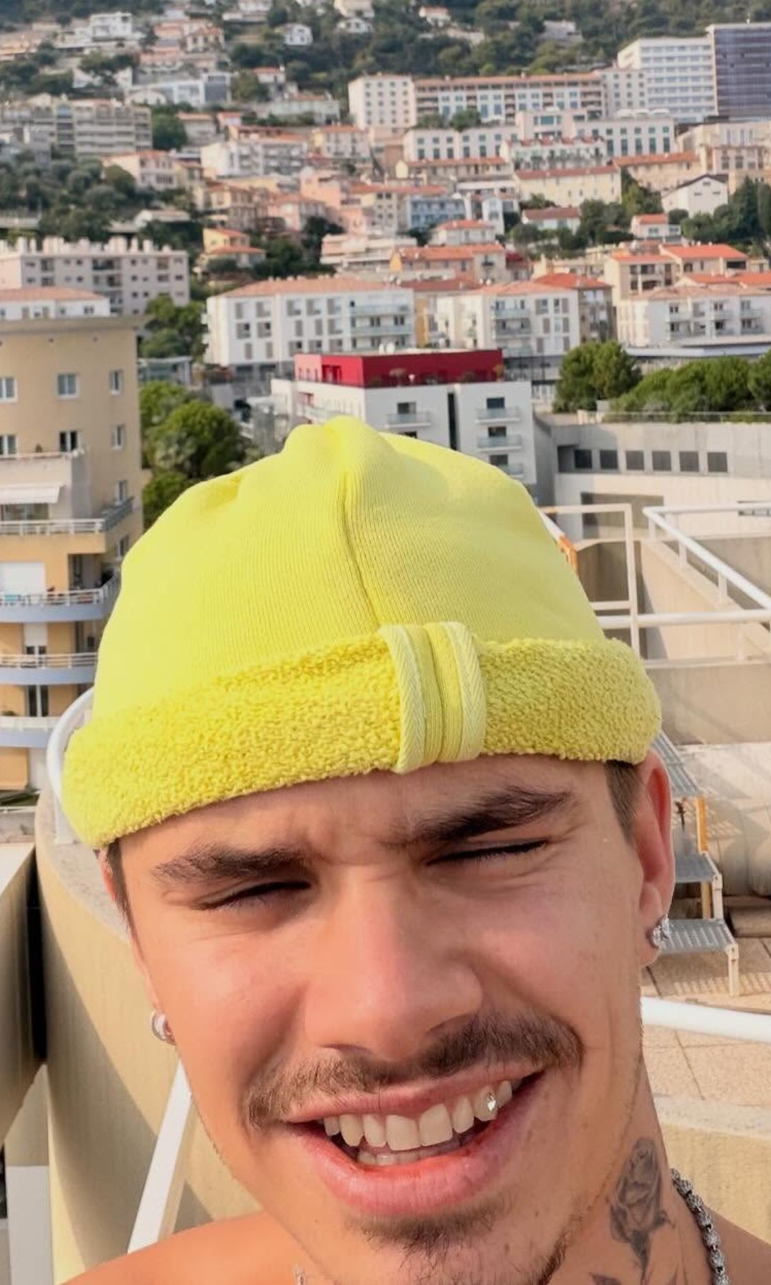 Romeo Beckham smiles for a selfie in a yellow beanie