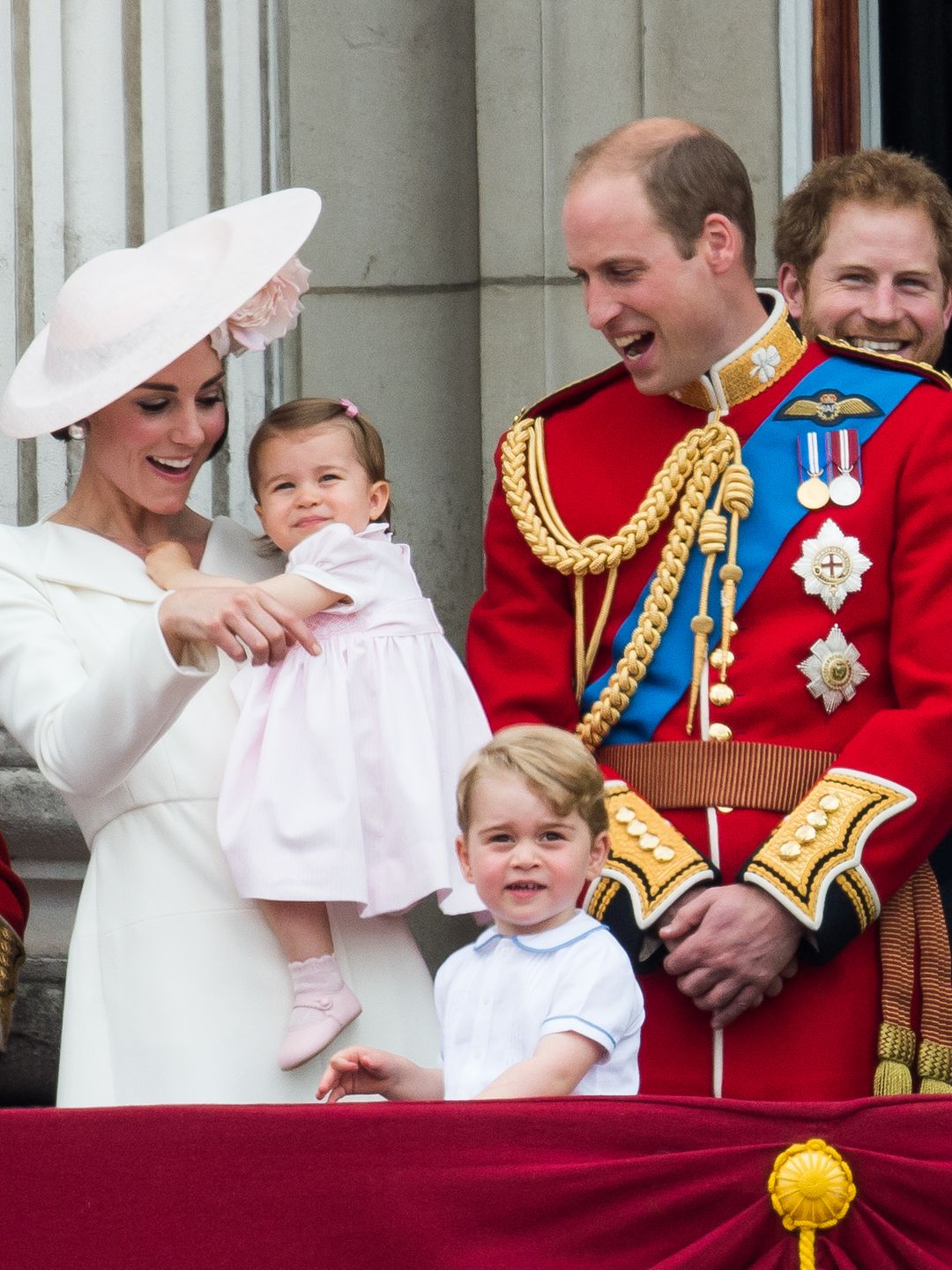 Kate Middleton holding a baby Princess Charlotte alongside Prince George, Prince William and Prince Harry