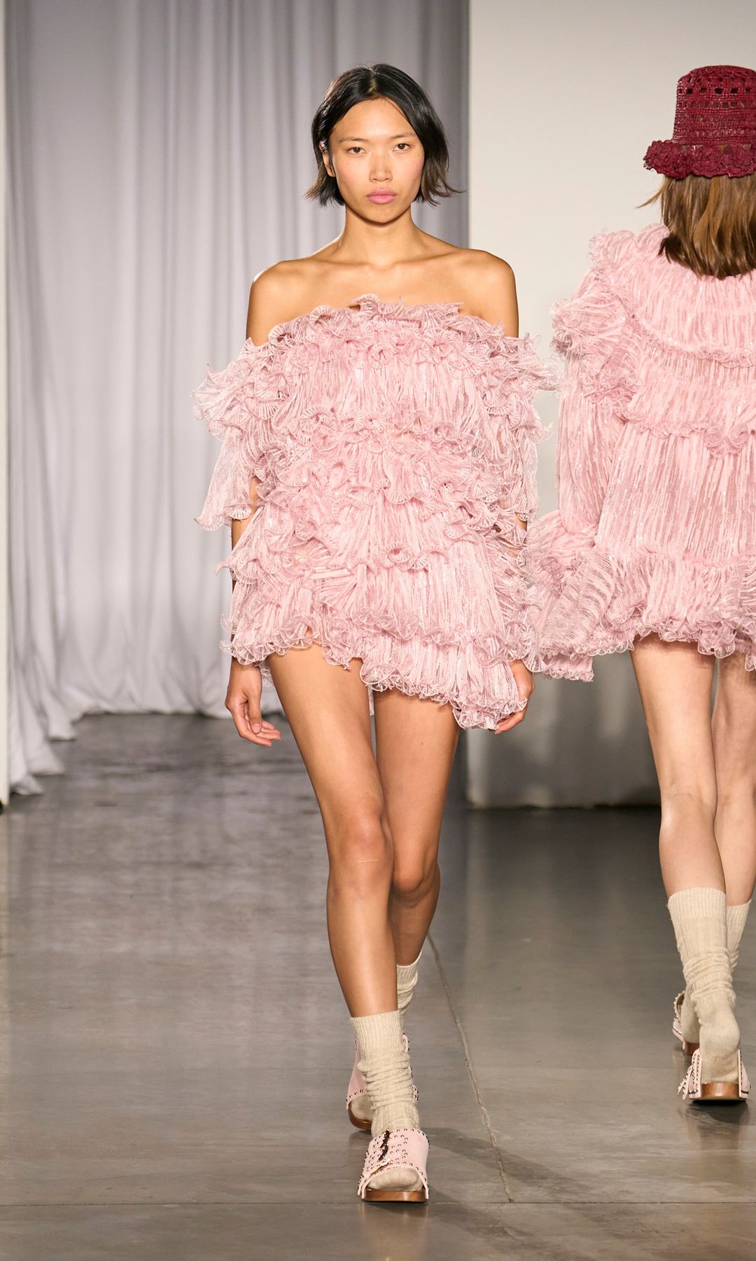 A baby pink ruffled off the shoulder mini dress, teamed with sandals and flat shoes - on the runway at Aknvas