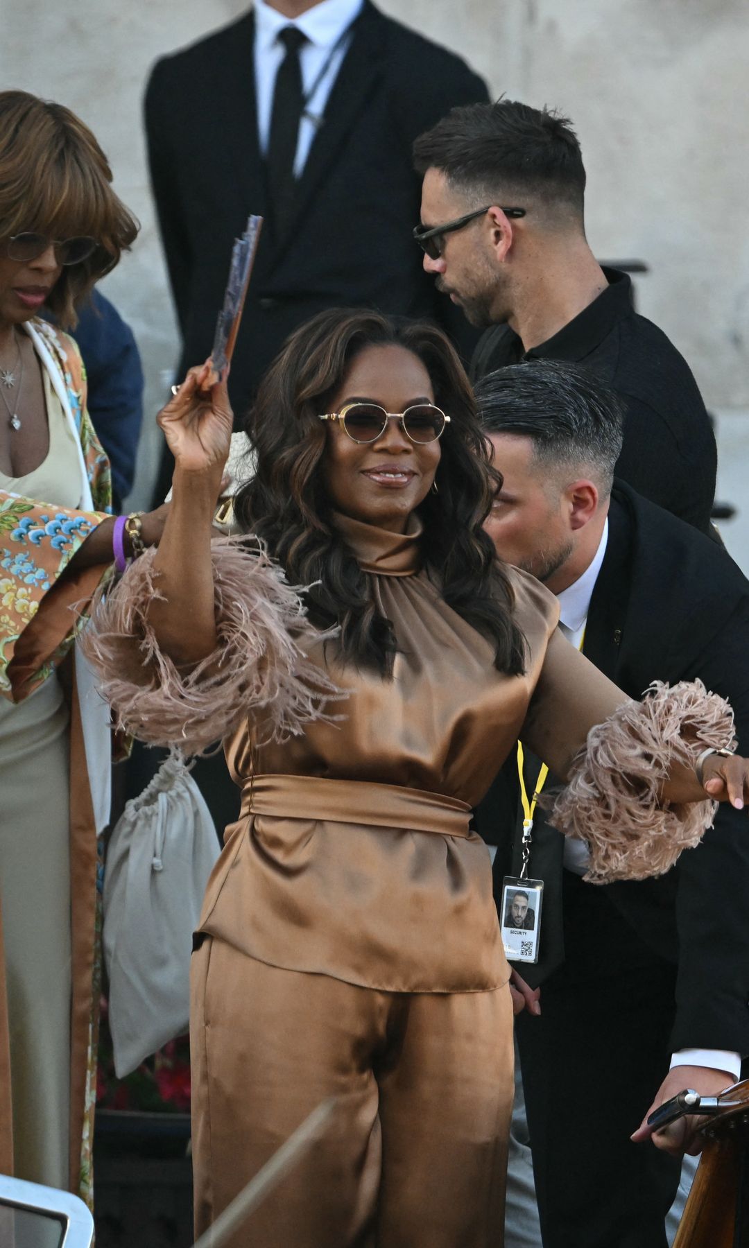 Oprah Winfrey wore a bronze satin outfit with feathered sleeves and wide-leg trousers, arriving in Venice for the Bezos wedding