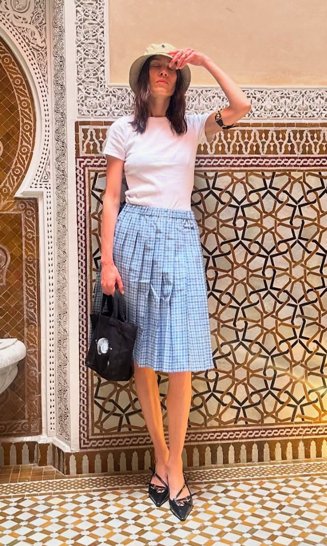 Alexa Chung poses in a plaid midi skirt, slingback heels and plain white tee while on holiday