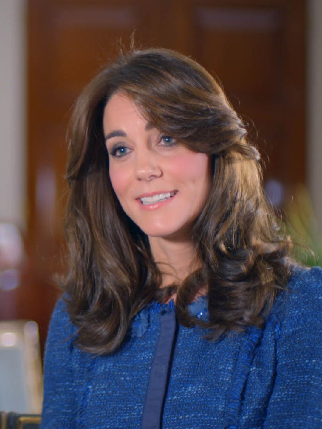 Kate Middleton in a blue jumper sat inside a living room