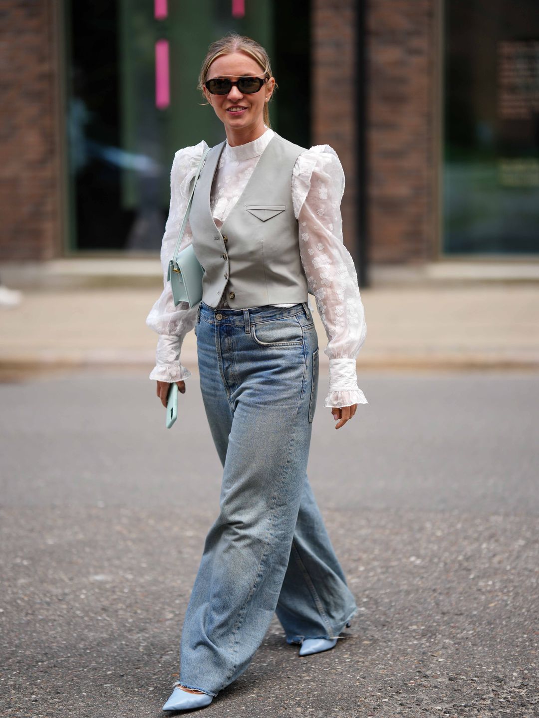 A Copenhagen Fashion Week guest wears a grey waistcoat with a semi-sheer blouse 
