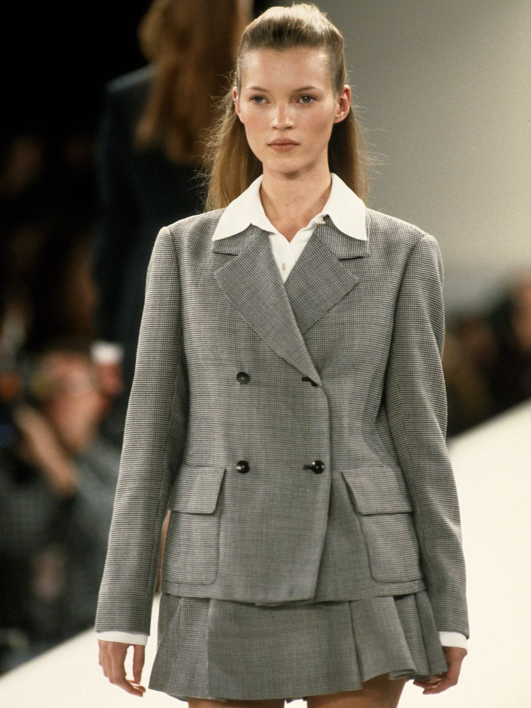 Kate Moss walks the Isaac Mizrahi Spring show in 1994 wearing a grey mini skirt and blazer combo