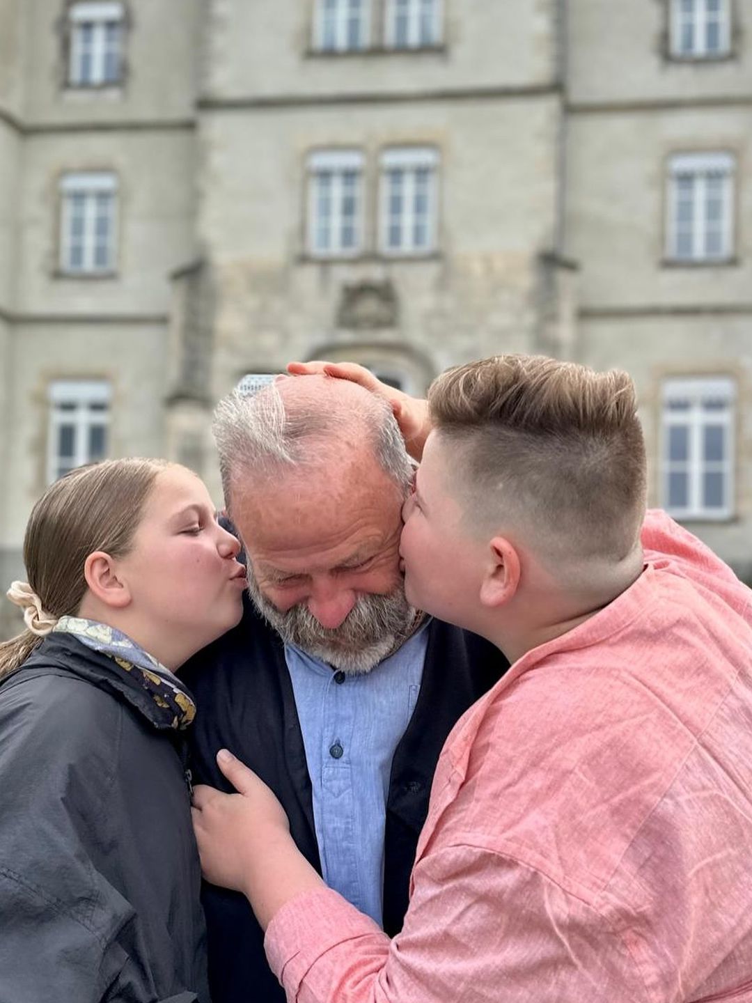 two children kissing their father on cheek