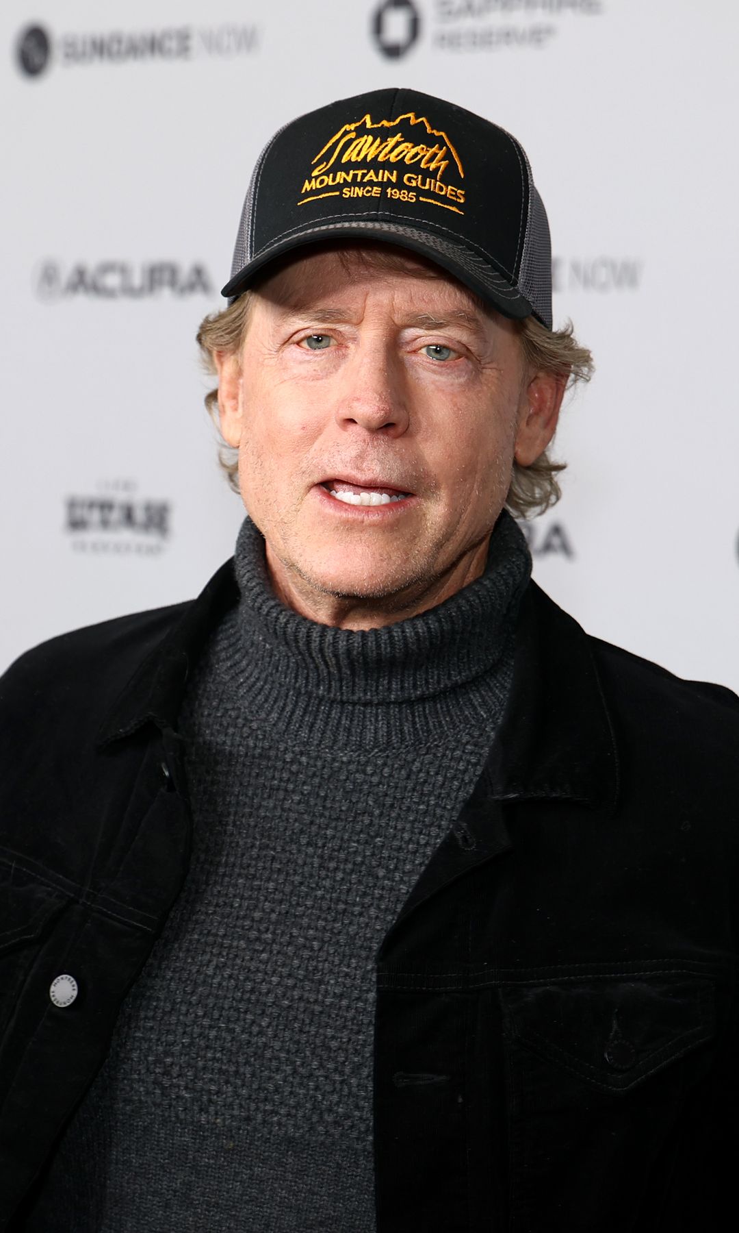 Greg Kinnear in a black outfit and cap