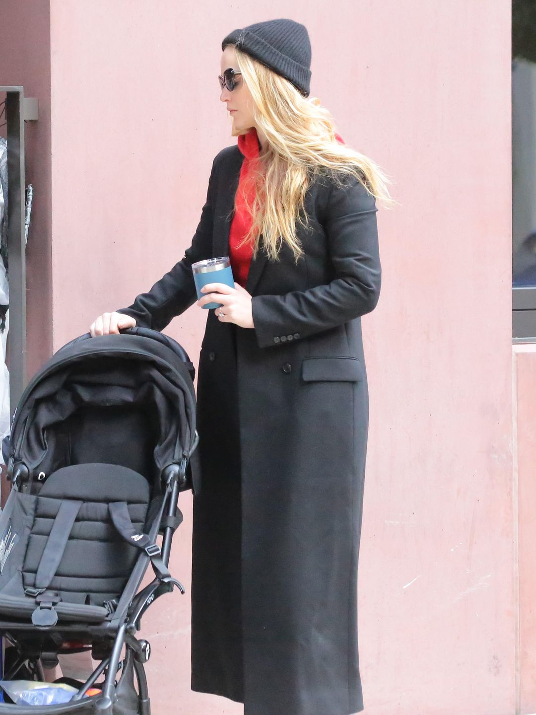 Jennifer Lawrence wearing a red hoodie under a black tailored coat 