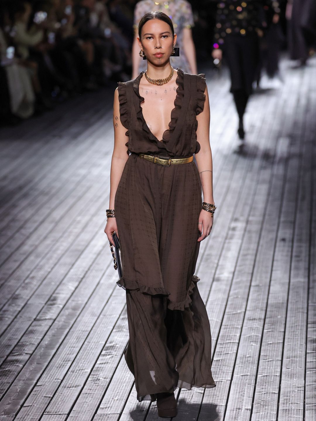 Quannah Chasinghorse walks the runway during the Chanel Womenswear Fall/Winter 2024-2025 show in a plunging neckline brown sheer gown