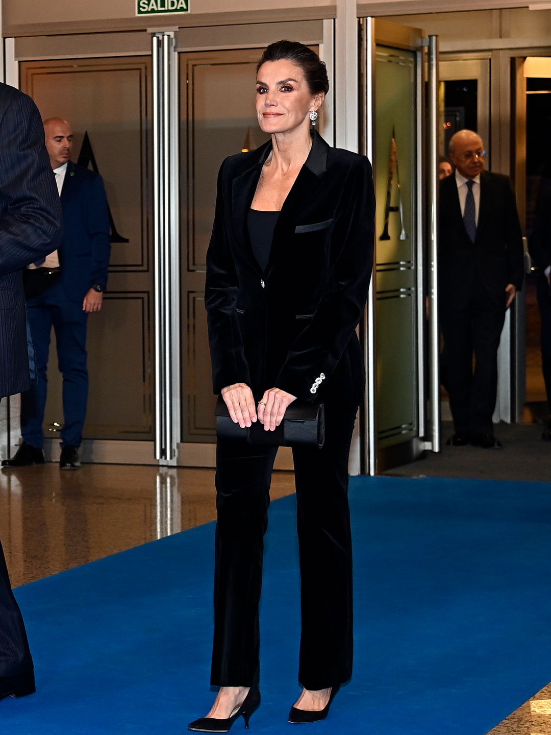  Queen Letizia of Spain wears a velvet black suit and heels, an updo hairstyle and a pair of black heels while on offical royal business in Spain