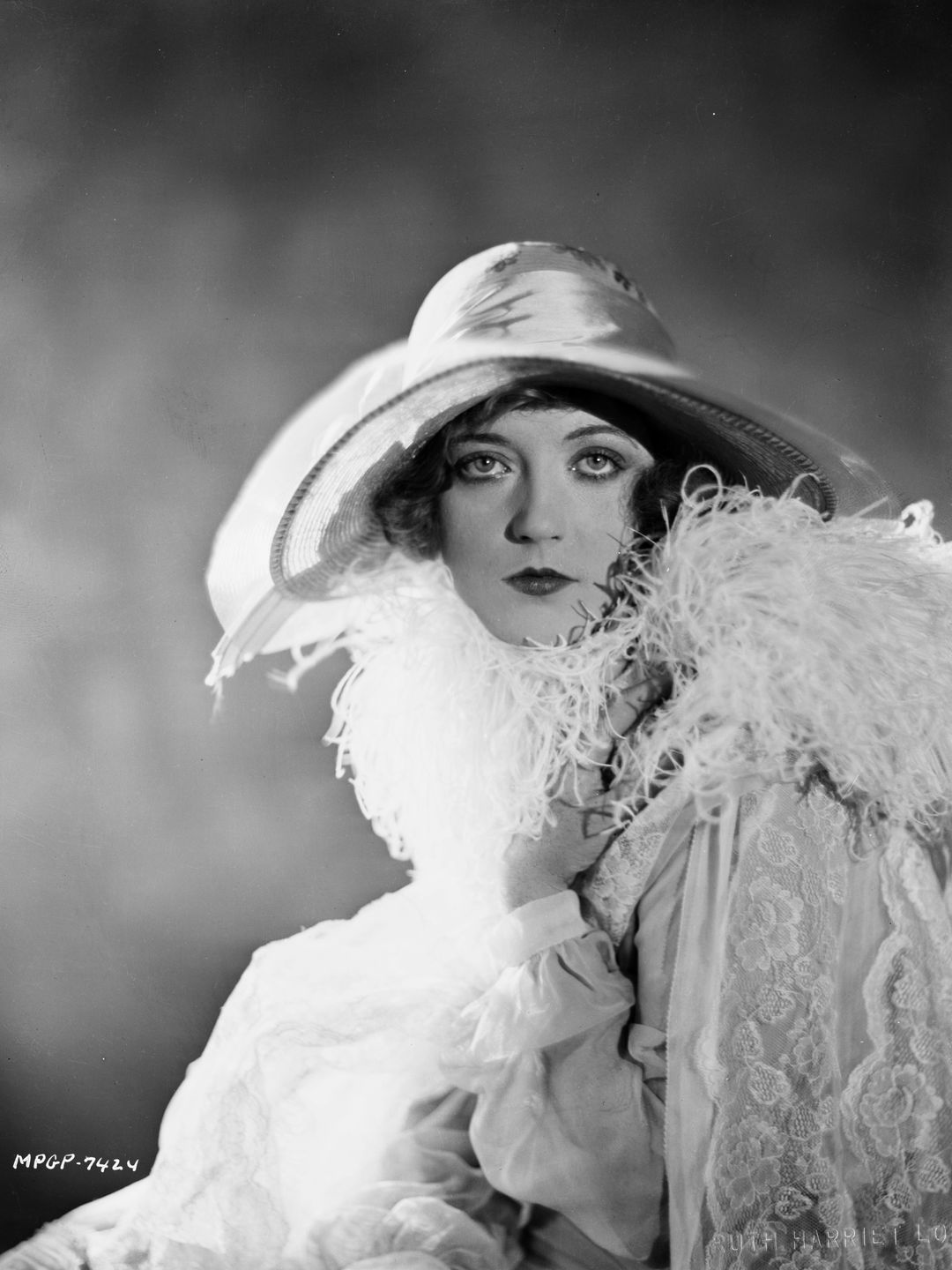 Marion Davies wears a wide-brimmed hat and feathered shawl