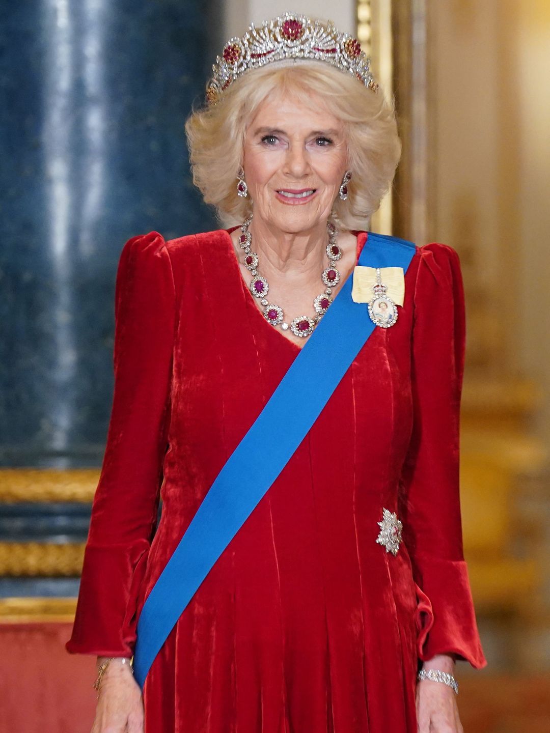 Queen Camilla in red velvet dress and ruby tiara